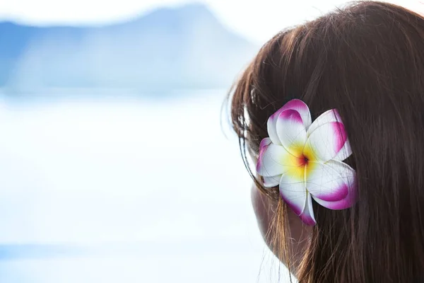 Mörka haired flicka klädd Hawaiian blomma tittar på ocean view — Stockfoto