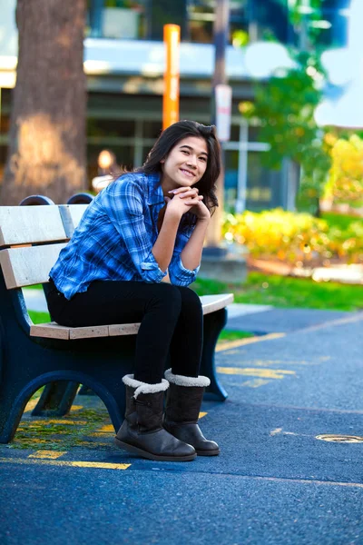 Tiener meisje rusten op houten bankje buiten aan het college — Stockfoto