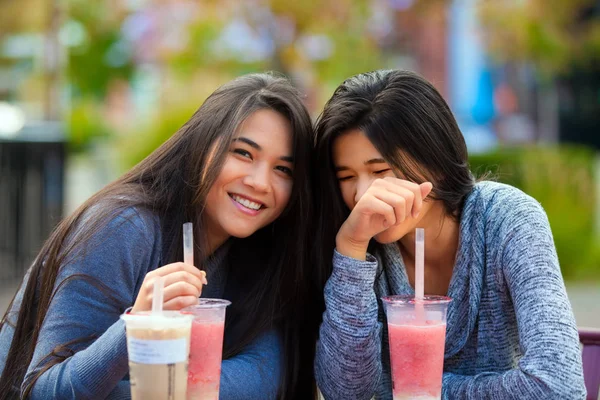 Две девочки-подростки в кафе на открытом воздухе пьют бобский чай вместе — стоковое фото