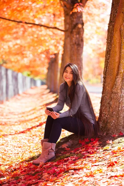 Teenie-Mädchen sitzt im Herbst unter bunten Ahornbäumen — Stockfoto