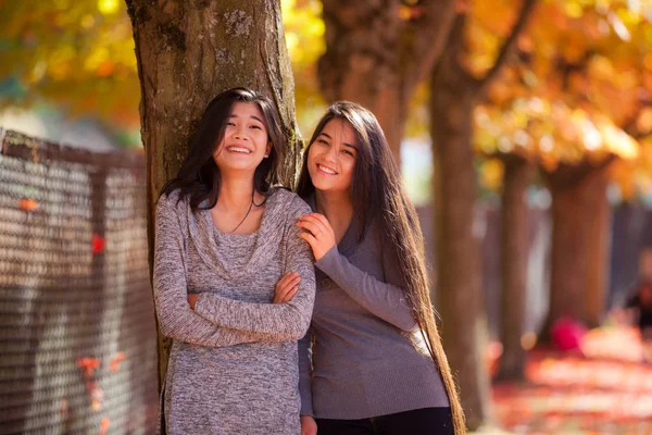Two teen girls standing next to maple tree in autumn — Stock Photo, Image