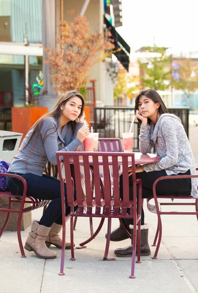 Two teen girls at outdoor cafe drinking boba tea together Royalty Free Stock Images