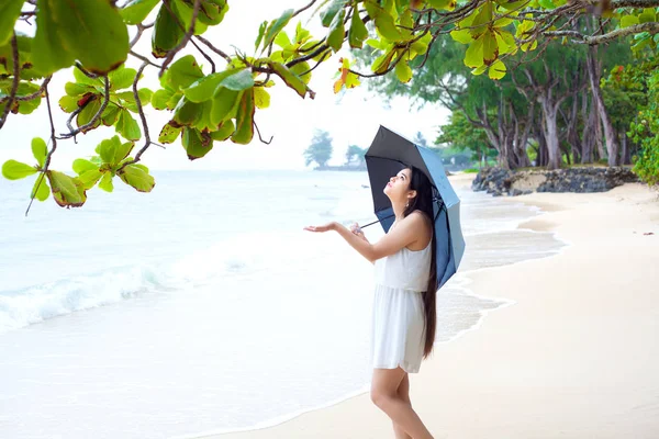 Mujer joven en la playa sosteniendo paraguas de comprobación de la lluvia —  Fotos de Stock