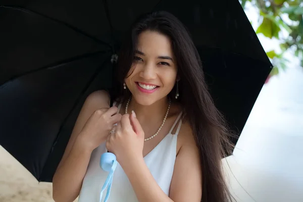 Belle femme souriante biraciale ou adolescent tenant parapluie dans le rai — Photo