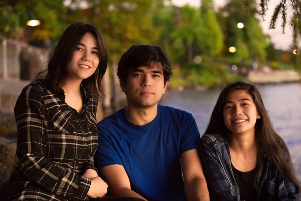 Young biracial Asian Caucasian young people by lake at sunset — Stock Fotó