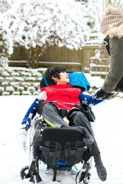 Mozgássérült fiú tolószékben télen havazik — Stock Fotó