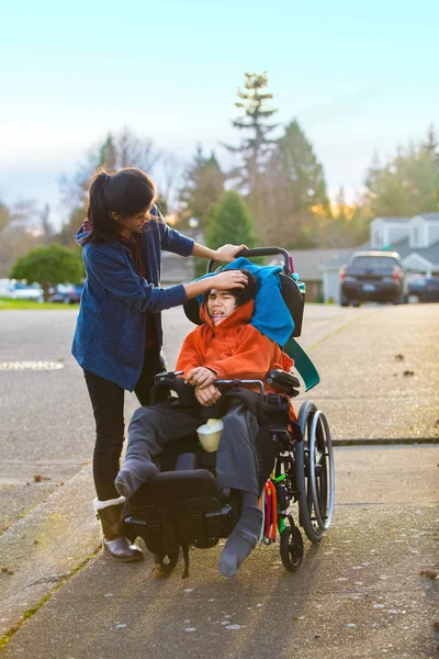 Teen girl comforting sad disabled little boy in wheelchair outdo — Stock Photo, Image