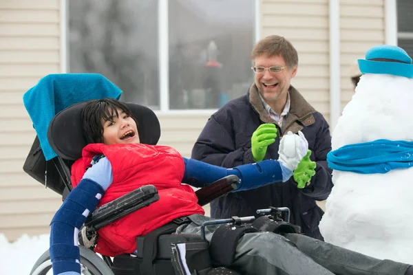 Père avec fils handicapé en fauteuil roulant jouant avec des boules de neige — Photo