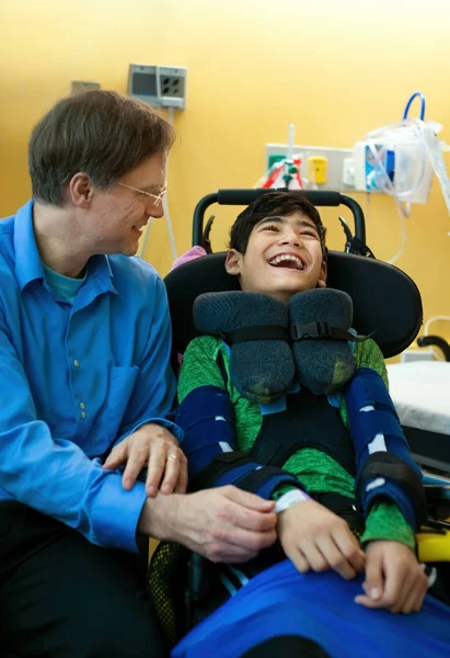 Padre hablando con hijo discapacitado en silla de ruedas en la sala de espera — Foto de Stock