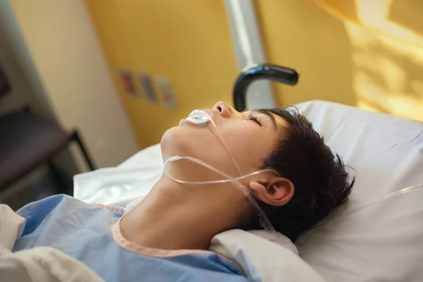Молодий підліток-хлопець несвідомий у лікарняній кімнаті відновлення на Ґурні — стокове фото