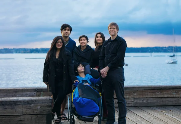 Mixed race family with disabled child in wheelchair by lake — Stock fotografie