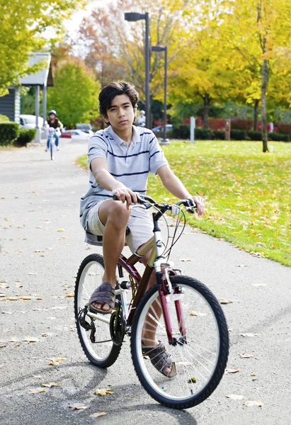Biracial dospívající chlapec jízda na kole v parku na slunný den — Stock fotografie
