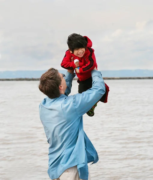 Caucasian father lifting up disabled little boy over head outdoo — ストック写真