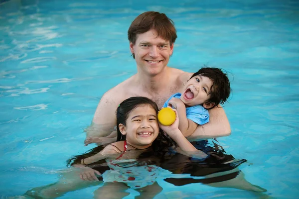 Кавказский отец в бассейне с расовыми детьми, держит инвалида — стоковое фото