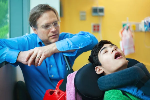 Otec hlídá postiženého syna, jak spí na vozíčku v hospitu — Stock fotografie
