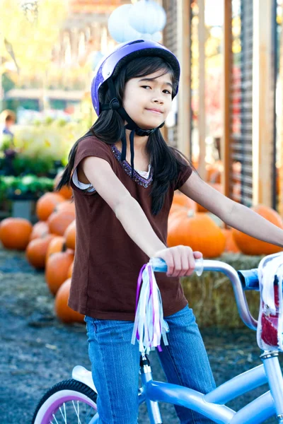 Petite fille biraciale à vélo portant un casque de vélo — Photo