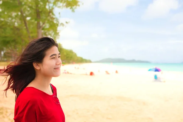 笑顔のプロフィールアジアの10代の少女は 青い海を見てビーチに立っていますオアフ島の空のワイマナロビーチ 明るい曇りと風の強い日にハワイ — ストック写真