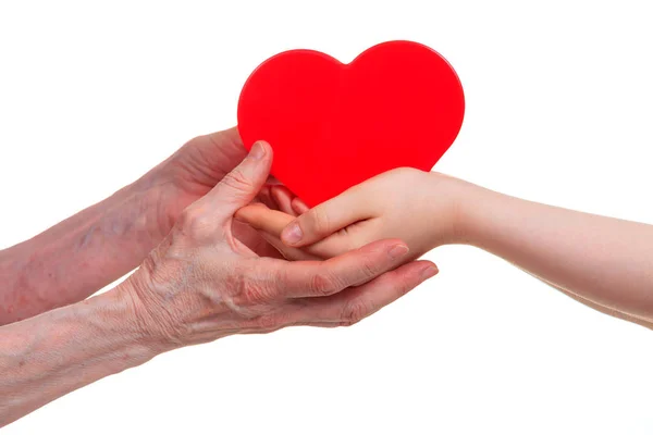 Oude en jonge handen met rood hart, geïsoleerd op een witte achtergrond. — Stockfoto