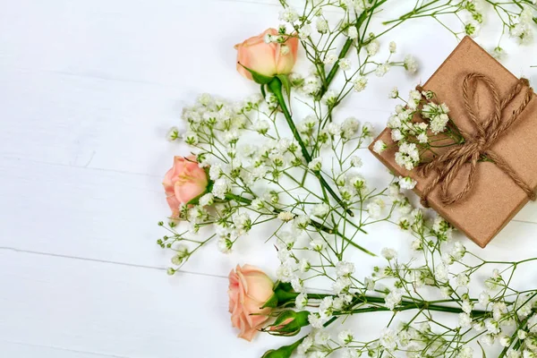 Fiori con una scatola regalo su tavolo di legno bianco, stile flat lay — Foto Stock