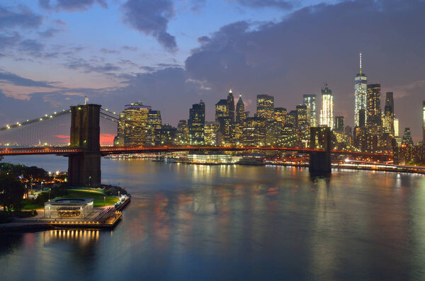 Manhattan skyline with Brooklyn Bridge at sunset.