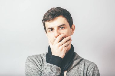 Adam gülüyor ve eliyle ağzını kapatıyor.