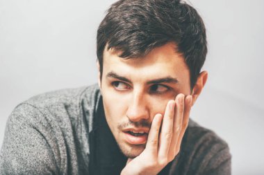 Adam çenesini elinde tutuyor.