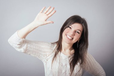 Gri arka planda el sallayan güzel kız