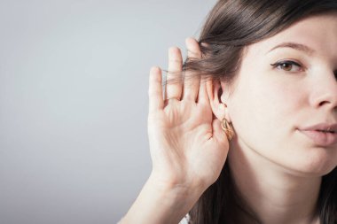 Kız gri arka planda kulak misafiri oluyor.