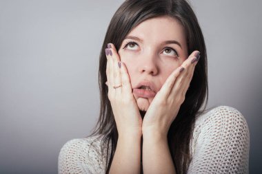 Gri arka planda şokta olan kadın