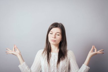 Kız gri arka plan üzerine meditasyon yapıyor.