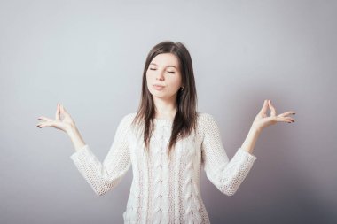 Kız gri arka plan üzerine meditasyon yapıyor.