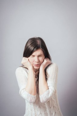 Kız gri arka planda kulaklarını kapatır.