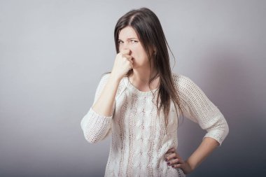 Gri arka planda kız kokuyor.