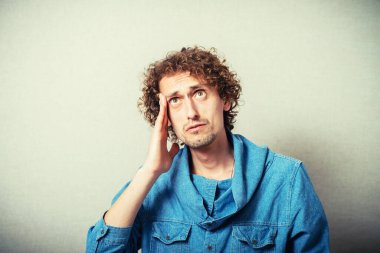 Önemli bir şey düşünen çekici bir adam. Elini şakağına dayayıp kameraya bakıyor.