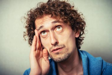 Önemli bir şey düşünen çekici bir adam. Elini şakağına dayayıp kameraya bakıyor.