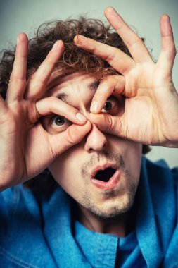 Elleri gözlerinde, parmaklarından bakan komik bir adam.