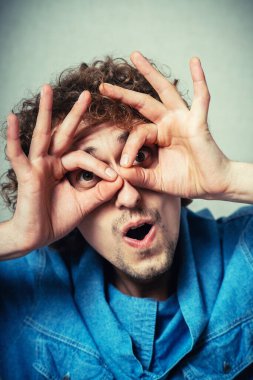 Elleri gözlerinde, parmaklarından bakan komik bir adam.