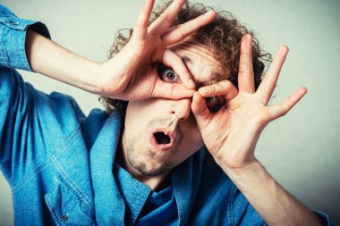 Elleri gözlerinde, parmaklarından bakan komik bir adam.