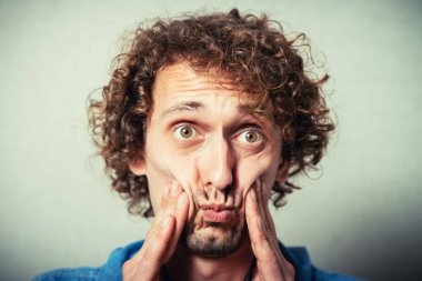 Gri arka planda diş ağrısı olan genç bir adam.