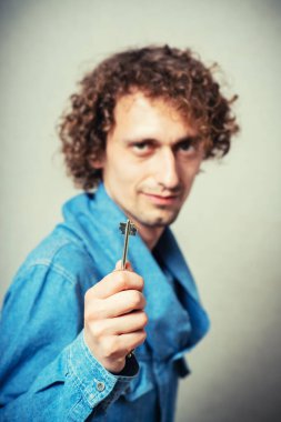 Anahtarı gri arka planda tutan adam.