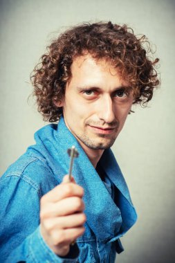 Anahtarı gri arka planda tutan adam.