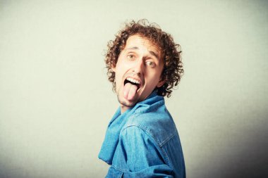 Adam gri arka planda dilini gösteriyor