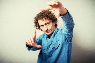 Gri arka planda fotoğraf çeken genç adamın portresi