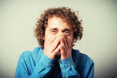 Genç adam ağzını kapatıyor.