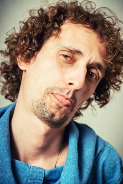 Adam gri arka planda dilini gösteriyor