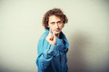 Genç ve yakışıklı bir adam. Jest yap. Gri bir arkaplanda