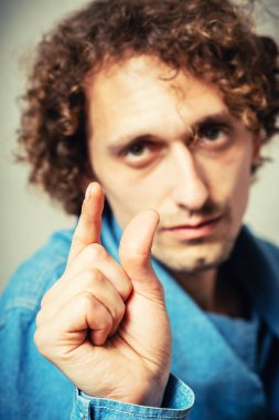 Genç ve yakışıklı bir adam. Jest yap. Gri bir arkaplanda