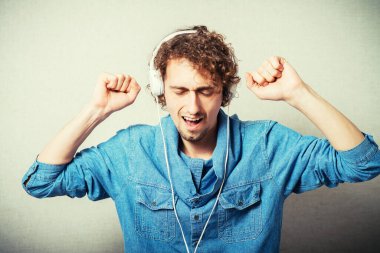 Kıvırcık adam kulaklıkla müzik dinliyor, beyaz, dans ediyor.