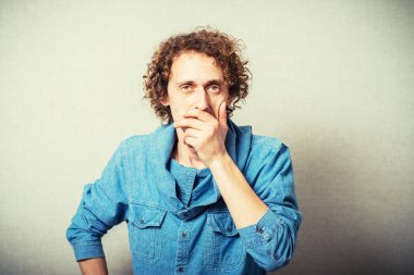 Kıvırcık saçlı adam ağzını kapatıyor.