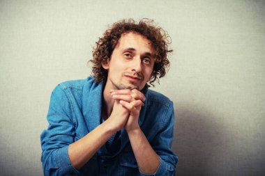 Kıvırcık saçlı adam çenesini eline dayadı.